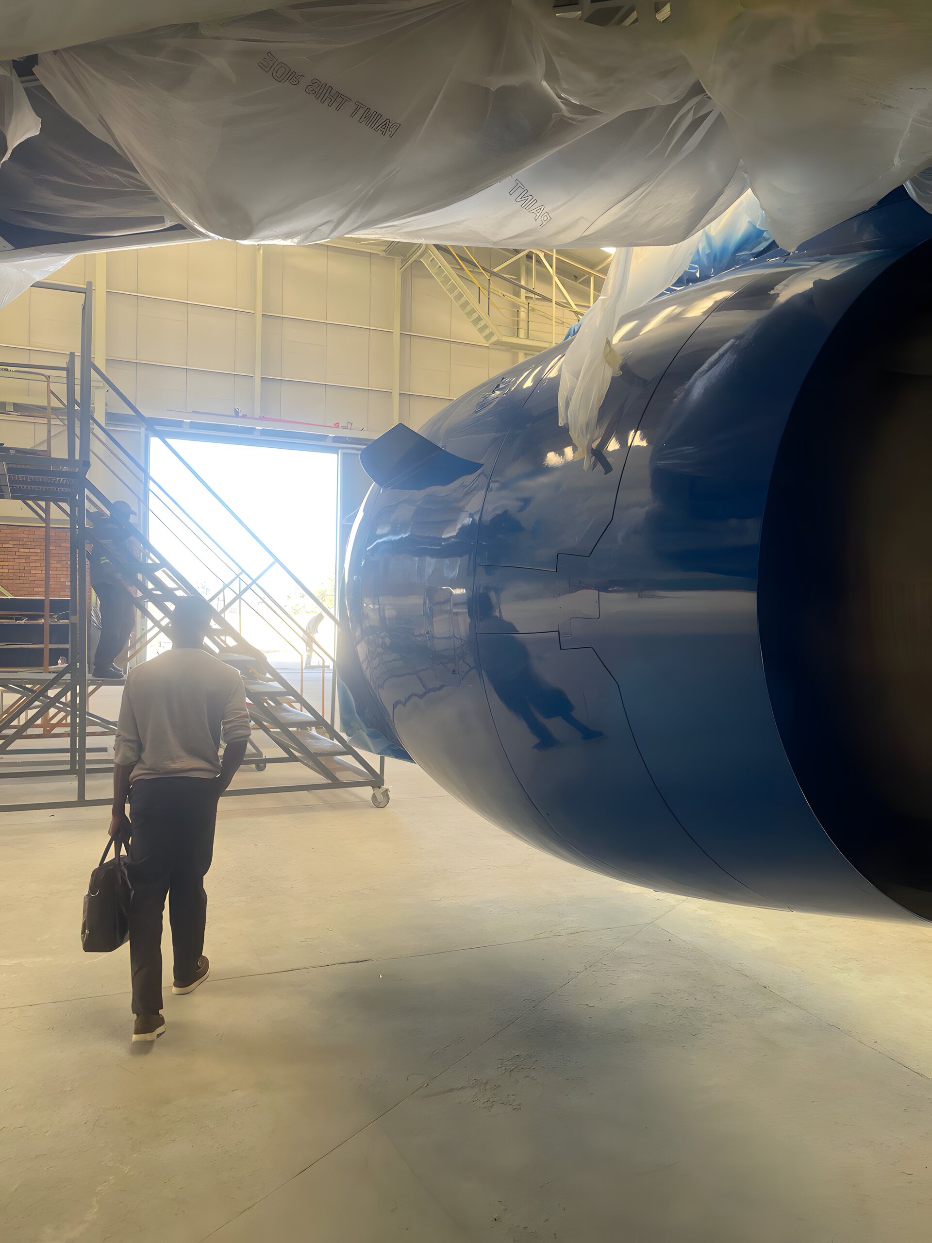 An engineer walks toward a wide-body engine under maintenance in the Ubunye hangar, Johannesburg
